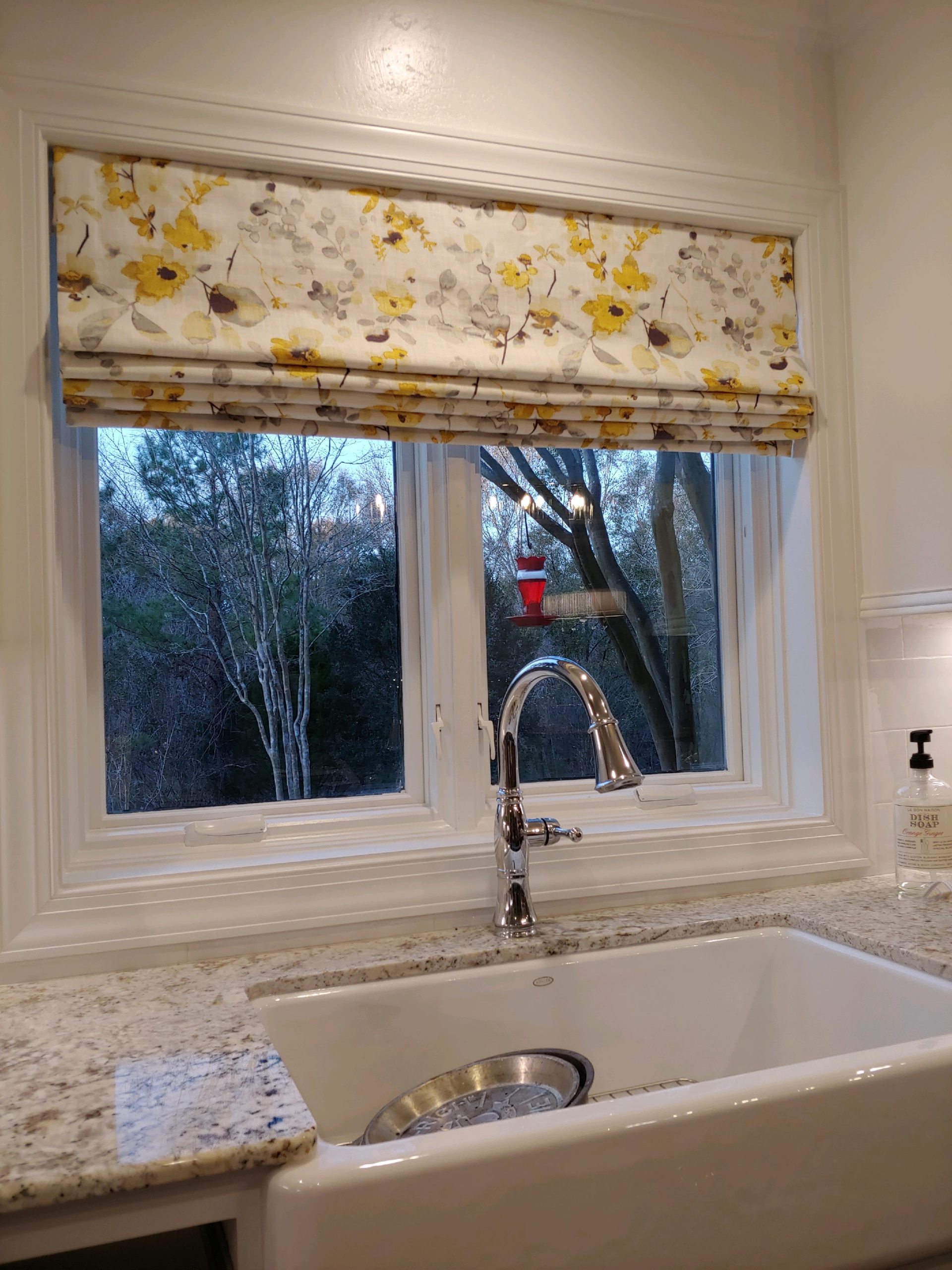 Fabric Roman blind with horizontal folds over a kitchen window